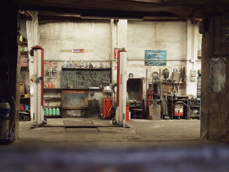 Inside Ben's shop — a two-post lift bay with a wall of hand tools